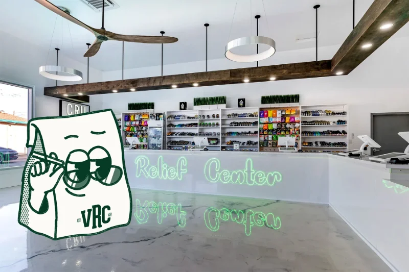 Interior of dispensary with white display shelves stocked with cannabis products and a branded mascot logo overlay