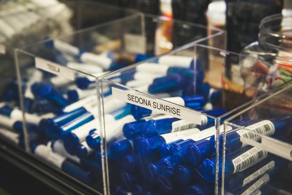 Cannabis dispensary display case showing labeled pre-roll products including Sedona Sunrise strain, representing organized product inventory at a local dispensary.