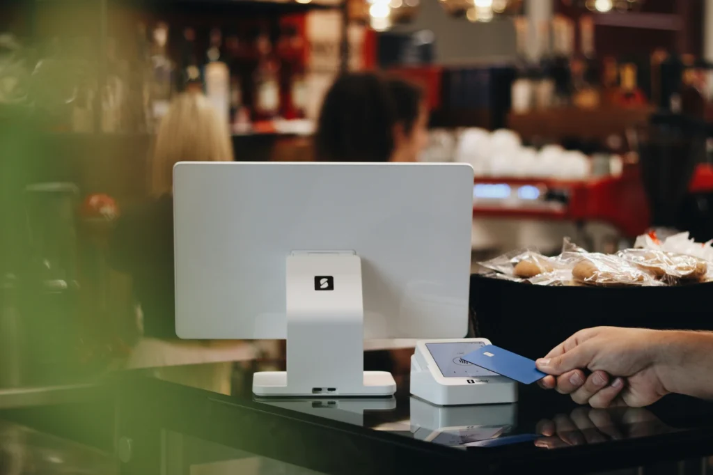 Customer tapping a card at a retail checkout counter, representing the sequencing that makes dispensary internet marketing actually work