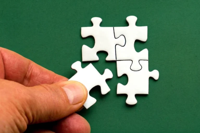 Hand connecting white puzzle pieces on a green background, representing how dispensary internet marketing channels work together